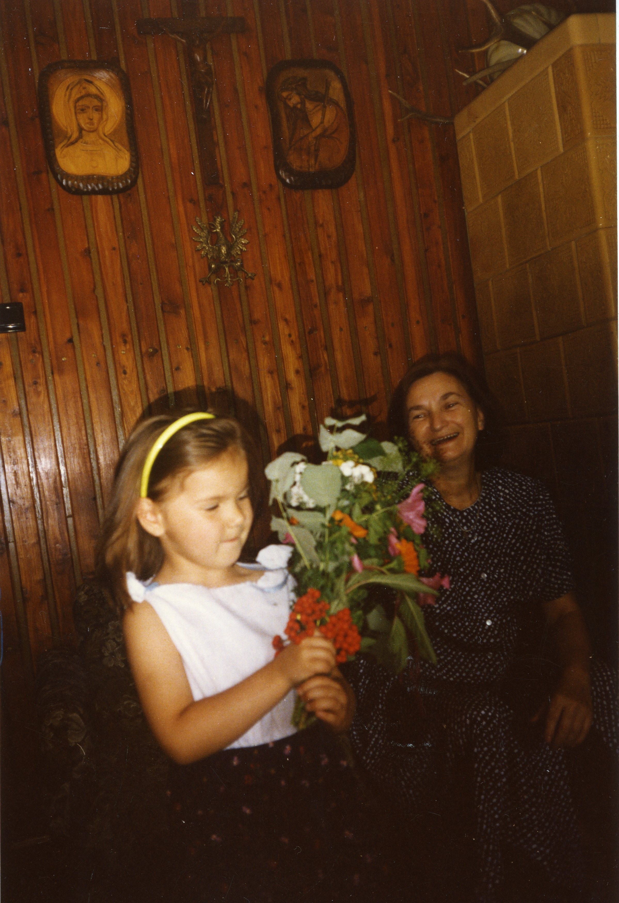 Babcia i mała dziewczynka. Dziewczynka w rękach trzyma bukiet kwiatów